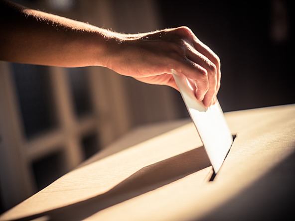 person posting their vote in ballot box